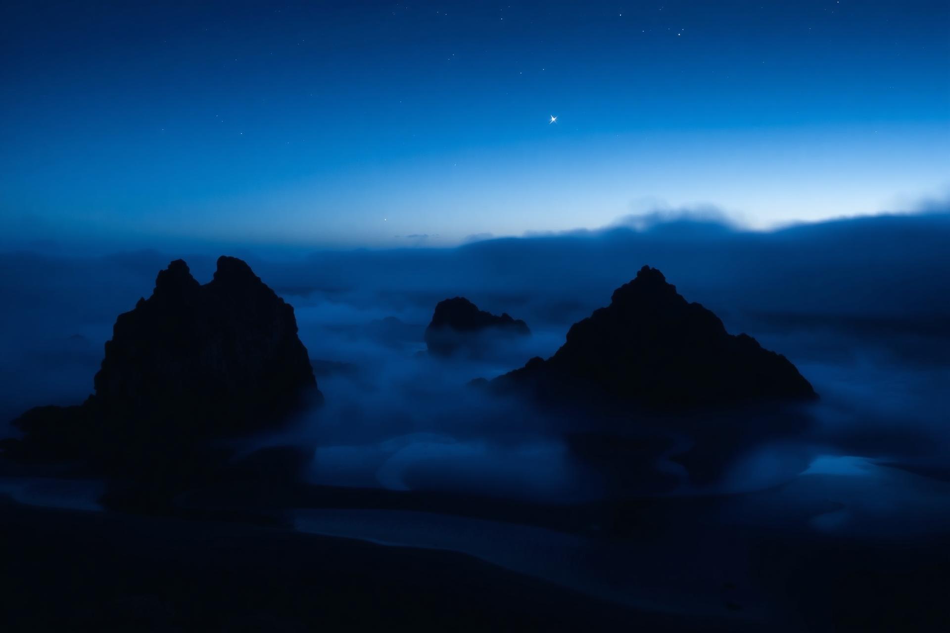 A misty Oregon coast under a deep midnight sky.